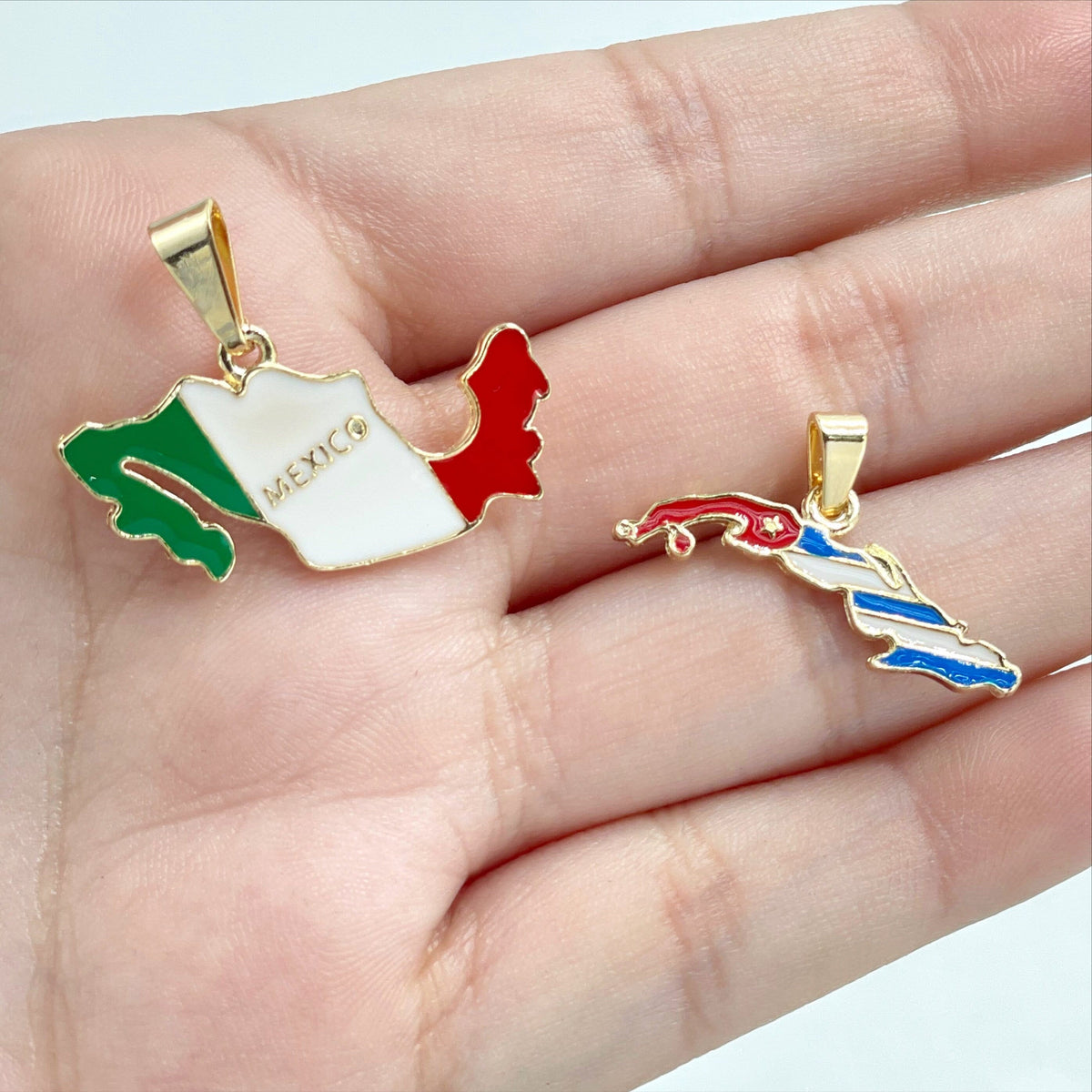 May include: Two gold-colored pendants shaped like the outlines of Mexico and Cuba. The Mexico pendant is green, white, and red, with the word "MEXICO" written on the white portion. The Cuba pendant is red, white, and blue.